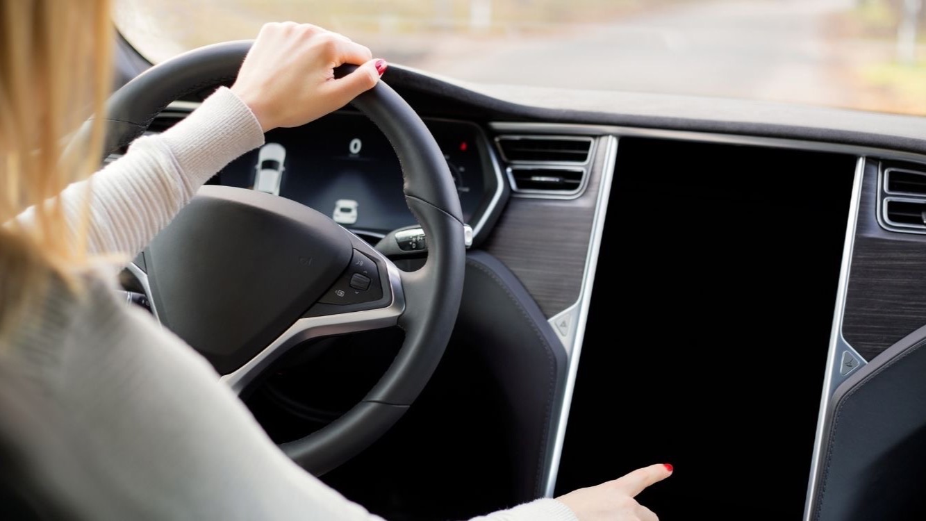 Conductor al volante de un coche eléctrico en carretera