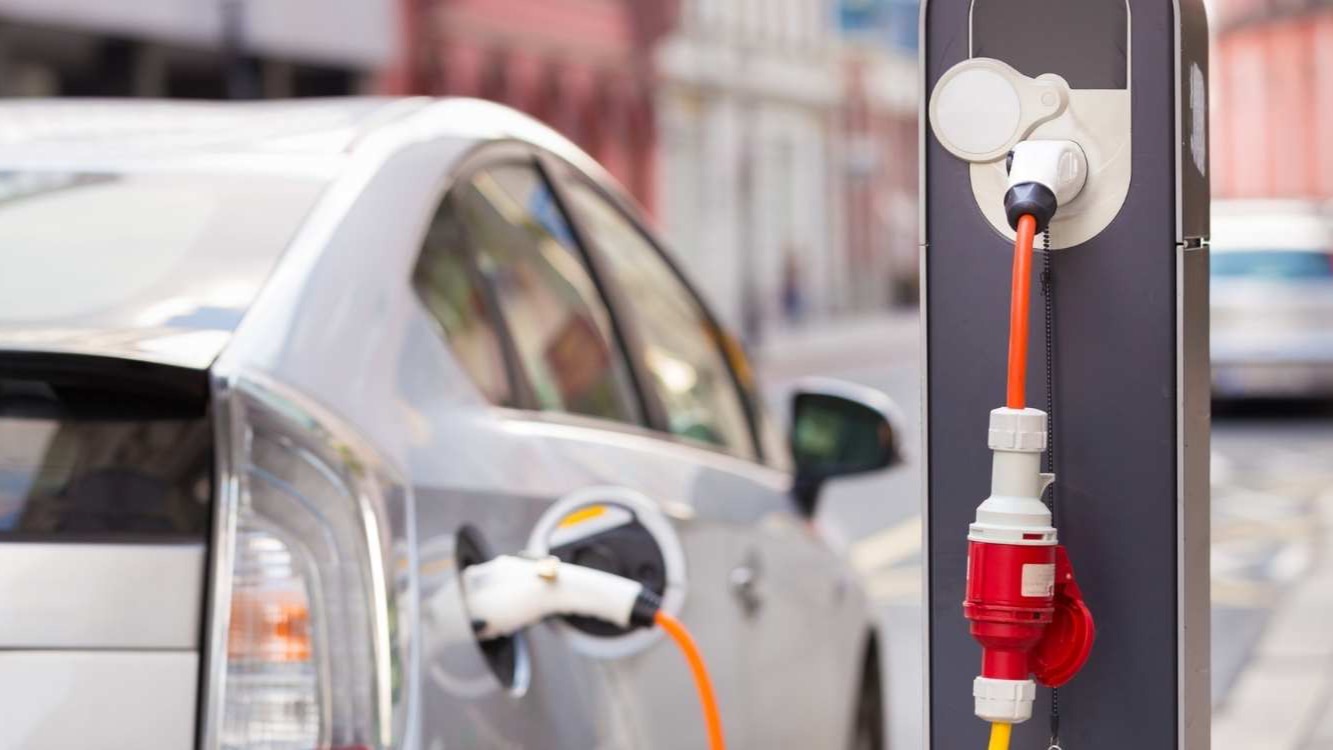 Coche eléctrico enchufado junto a documentación de una subvención